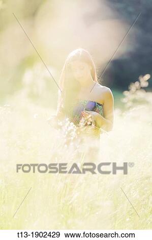 Stock Photo - Young woman is collecting flowers. Fotosearch