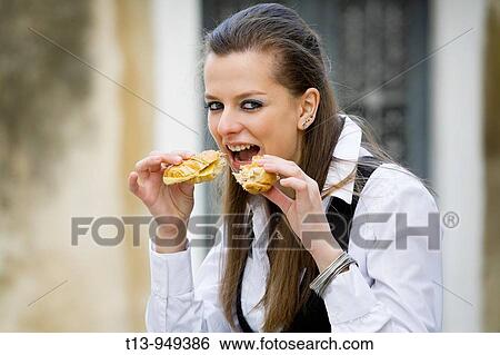 Stock Photograph - Young woman is eating two sandwiches at the same time. Fotosearch