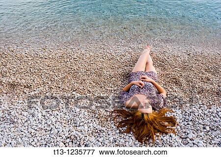 Young woman is lying on the beach with her hair spread on sand View Large Photo Image Stock Photo - Young woman is lying on the beach with her hair spread on sand. Fotosearch