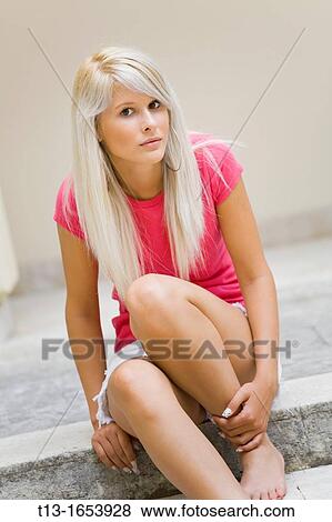 Stock Photo - Young woman is sitting on a step. Fotosearch