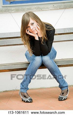 Young woman is sitting on a wooden bench View Large Photo Image Stock Image - Young woman is sitting on a wooden bench. Fotosearch