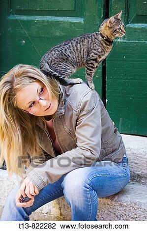 Young woman is sitting on porch with cat standing on her shoulders View Large Photo Image Stock Image - Young woman is sitting on porch with cat standing on her shoulders. Fotosearch