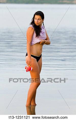 Young woman is standing in a shallow water with a toy fish in hand View Large Photo Image Stock Image - Young woman is standing in a shallow water with a toy fish in hand. Fotosearch