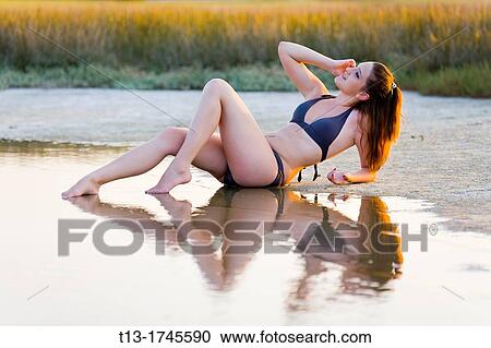 Young woman is stretching on a shoreline View Large Photo Image Stock Image - Young woman is stretching on a shoreline. Fotosearch