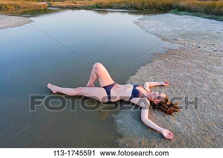 Young woman is stretching on a shoreline View Large Photo Image Stock Image - Young woman is stretching on a shoreline. Fotosearch