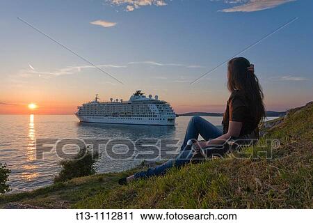 Stock Image - Young woman is watching a big ship during a sunset time, Rovinj in Croatia. Fotosearch