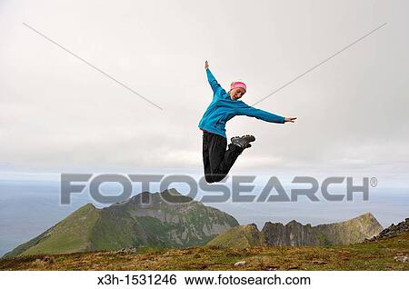 young woman jumping at the top of the Husfjellet mountain, Senja island County of Troms, Norway, Northern Europe View Large Photo Image Stock Photograph - young woman jumping at the top of the Husfjellet mountain, Senja island County of Troms, Norway, Northern Europe. Fotosearch