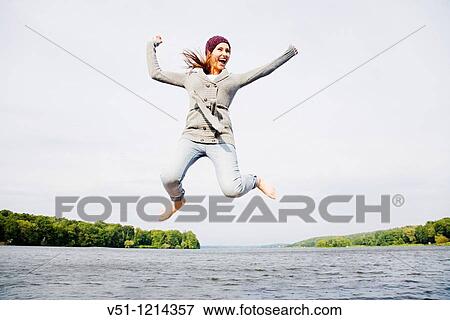 Stock Photo - Young woman jumping by the sea. Fotosearch