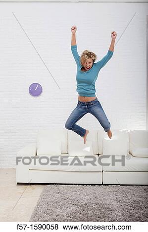 Young woman jumping for joy off her sofa View Large Photo Image Stock Photo - Young woman jumping for joy off her sofa. Fotosearch