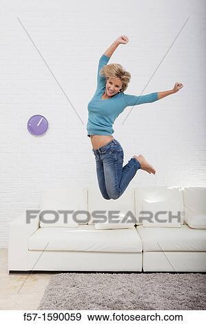 Young woman jumping for joy off her sofa View Large Photo Image Stock Photo - Young woman jumping for joy off her sofa. Fotosearch