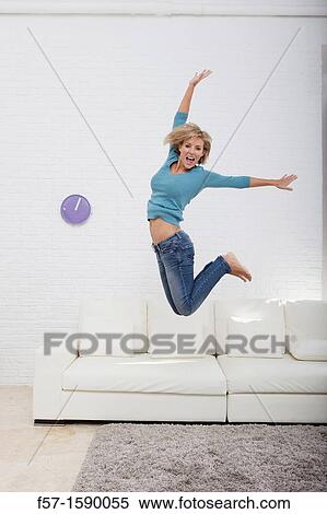 Young woman jumping for joy off her sofa View Large Photo Image Stock Photography - Young woman jumping for joy off her sofa. Fotosearch