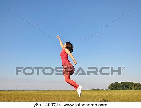 Young woman jumping in air View Large Photo Image Picture - Young woman jumping in air. Fotosearch