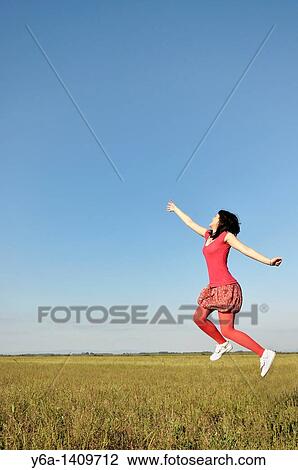 Young woman jumping in air View Large Photo Image Stock Image - Young woman jumping in air. Fotosearch