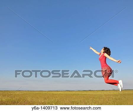 Stock Image - Young woman jumping in air. Fotosearch