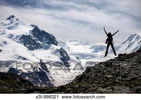 Stock Image - Young woman jumping in Gornetgrat glacier Switzerland. Fotosearch