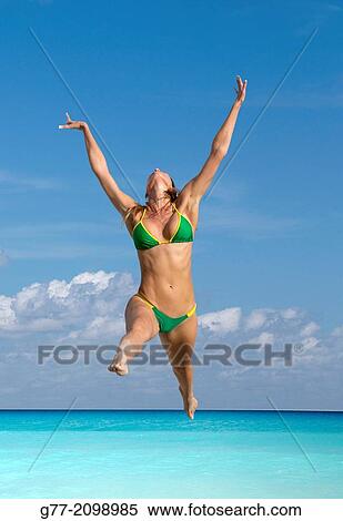 Stock Photography - Young woman jumping on the beach, Miami Beach, Florida, USA. Fotosearch