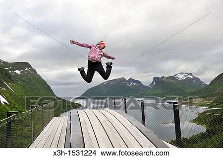 young woman jumping over the fjord Bergsfjorden Landscaping of the National Tourist Route The west coast of the island Senja has been selected as one of the most spectacular landscapes in Norway Senja island County of Troms, Norway, Northern Europe View Large Photo Image Picture - young woman jumping over the fjord Bergsfjorden Landscaping of the National Tourist Route The west coast of the island Senja has been selected as one of the most spectacular landscapes in Norway Senja island County of Troms, Norway, Northern Europe. Fotosearch