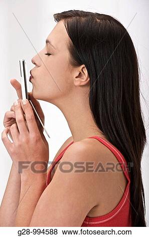 Stock Photo - young woman kissing her telephone. Fotosearch