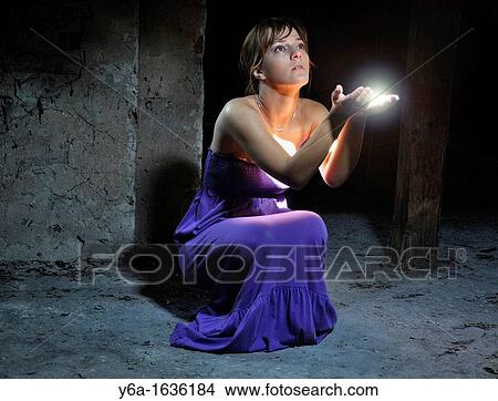 Young woman kneeling in attic capturing lightbeam between hands View Large Photo Image Picture - Young woman kneeling in attic capturing lightbeam between hands. Fotosearch