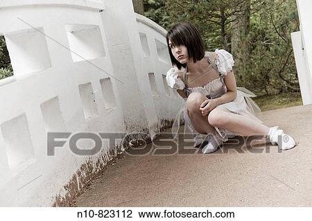 Young woman kneeling on a bridge. View Large Photo Image Stock Image - Young woman kneeling on a bridge.. Fotosearch