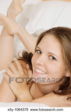 Young woman laying in bed View Large Photo Image Stock Photo - Young woman laying in bed. Fotosearch