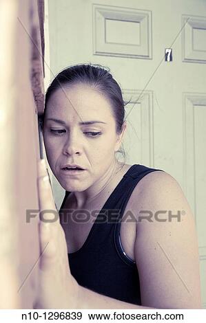 Stock Photo - Young woman leaning against a wall. Fotosearch