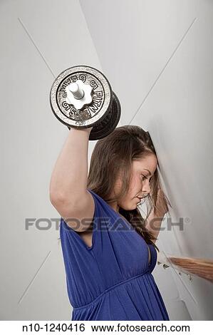 Stock Photograph - Young woman lifting weights. Fotosearch