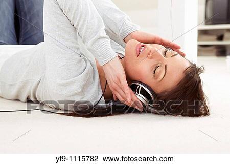 Young woman listening music lying on floor. View Large Photo Image Stock Image - Young woman listening music lying on floor.. Fotosearch