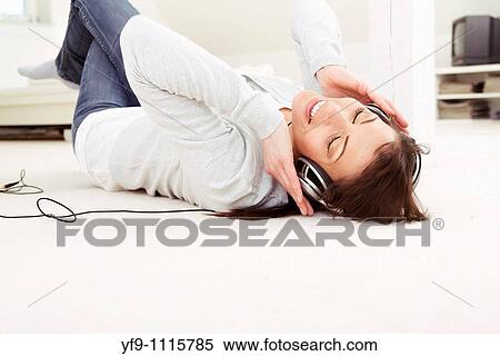 Stock Photography - Young woman listening music lying on floor.. Fotosearch