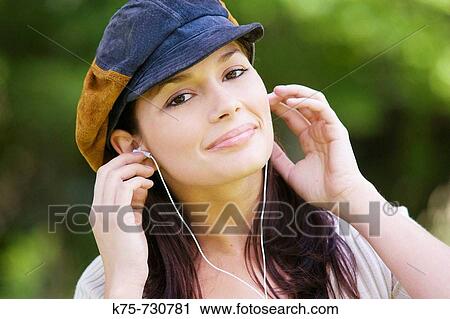 Stock Image - young woman listening to music on mp3 player. Fotosearch