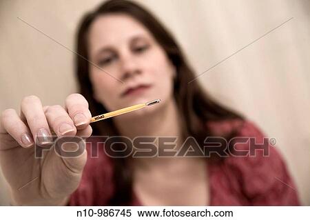 Stock Photography - Young woman looking at a thermometer. Fotosearch