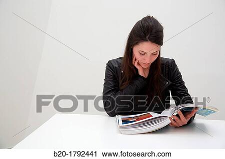 Stock Image - Young woman looking at exhibition catalog. David Hockney,? A Bigger Picture? exhibition, Guggenheim Museum, Bilbao, Biscay, Basque Country, Spain. Fotosearch