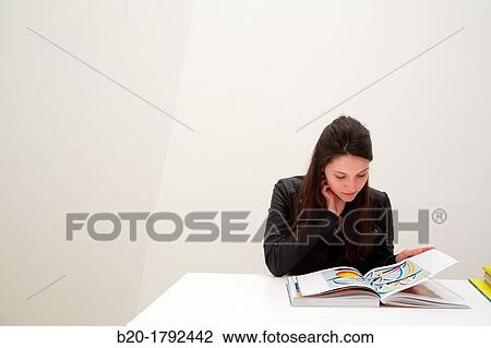 Stock Image - Young woman looking at exhibition catalog. David Hockney,? A Bigger Picture? exhibition, Guggenheim Museum, Bilbao, Biscay, Basque Country, Spain. Fotosearch