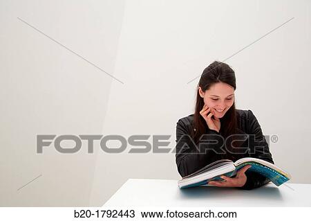 Stock Image - Young woman looking at exhibition catalog. David Hockney,? A Bigger Picture? exhibition, Guggenheim Museum, Bilbao, Biscay, Basque Country, Spain. Fotosearch