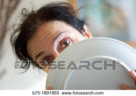 Young woman looking at the camera through a plate View Large Photo Image Stock Image - Young woman looking at the camera through a plate. Fotosearch