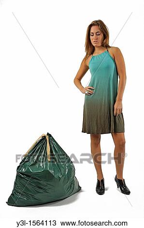 Stock Image - Young woman looking disgusted to a full trash bag. Fotosearch