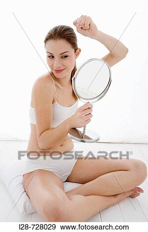 Stock Photo - Young woman looking in mirror,. Fotosearch