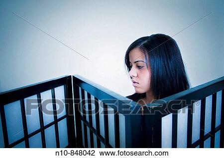 Stock Image - Young woman looking over the top of a screen.. Fotosearch