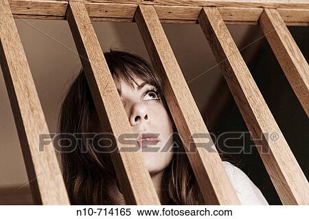 Young woman looking through the slats of a wood railing. View Large Photo Image Stock Photography - Young woman looking through the slats of a wood railing.. Fotosearch