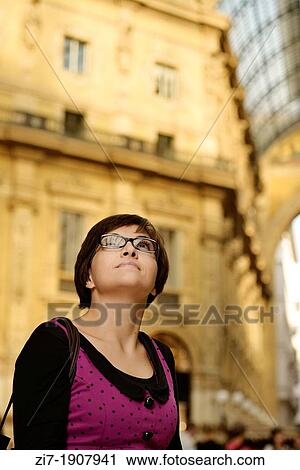 Stock Image - young woman looks at famous glass roof of historic arcade in city center. Fotosearch