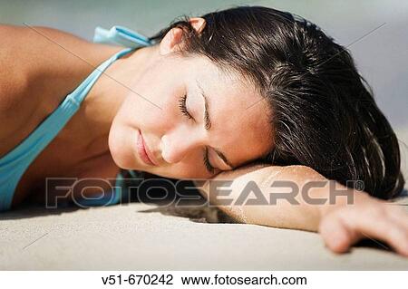 Young woman lying down at beach View Large Photo Image Stock Image - Young woman lying down at beach. Fotosearch