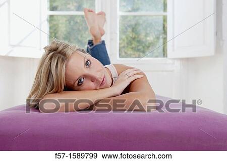 Young woman lying down in her living room View Large Photo Image Stock Photo - Young woman lying down in her living room. Fotosearch