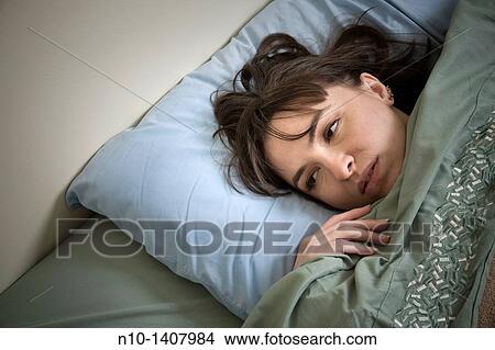 Picture - Young woman lying in bed. Fotosearch