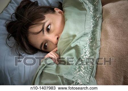 Stock Image - Young woman lying in bed. Fotosearch
