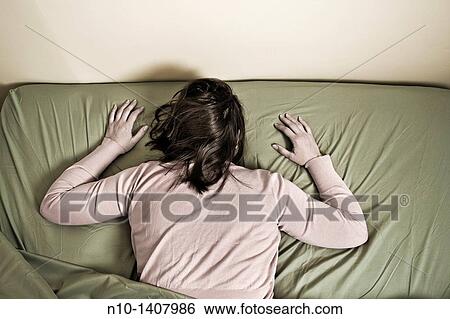 Stock Photograph - Young woman lying in bed. Fotosearch