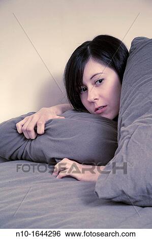 Stock Photograph - Young woman lying in bed. Fotosearch