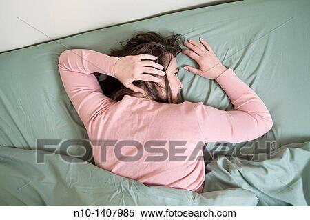 Stock Photography - Young woman lying in bed. Fotosearch