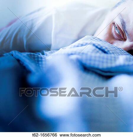 Young woman lying in bed with eyes open View Large Photo Image Stock Photograph - Young woman lying in bed with eyes open. Fotosearch
