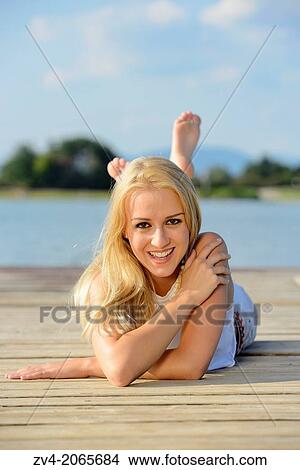 Young woman lying on a jetty at a lake in Austria. View Large Photo Image Picture - Young woman lying on a jetty at a lake in Austria.. Fotosearch