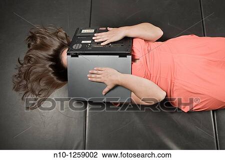 Young woman lying on a mat, a laptop computer covering her face View Large Photo Image Stock Image - Young woman lying on a mat, a laptop computer covering her face. Fotosearch